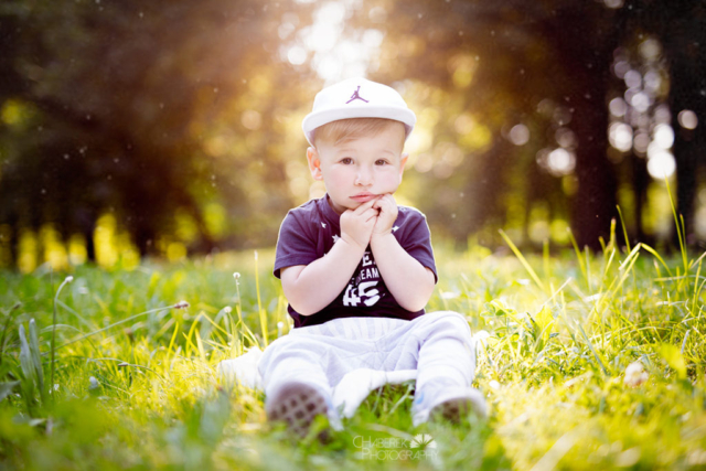 dwuletni chłopiec siedzący w parku na trawie