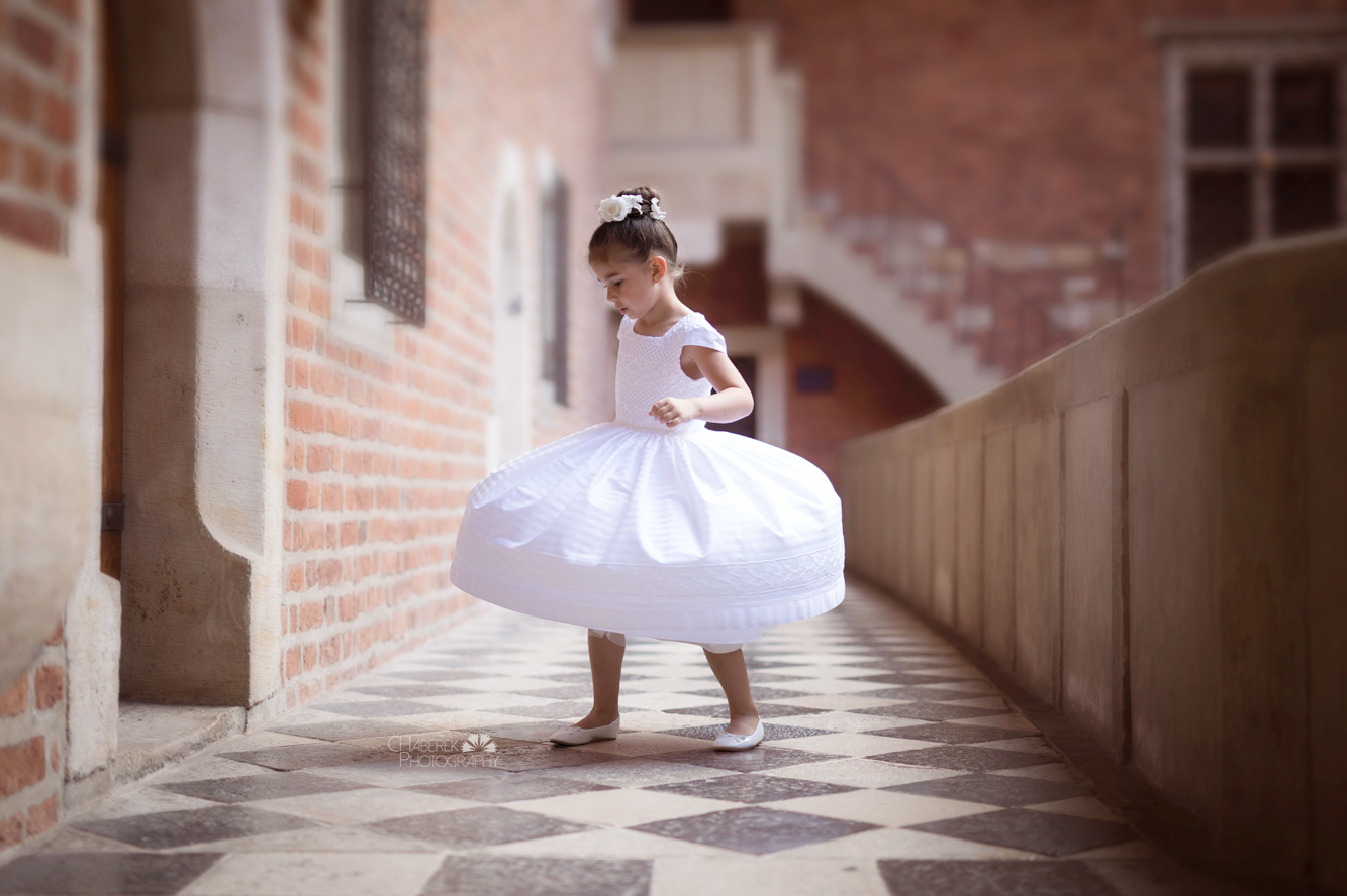 dziewczynka w białej sukience bawi się na dziedzińcu pałacyku