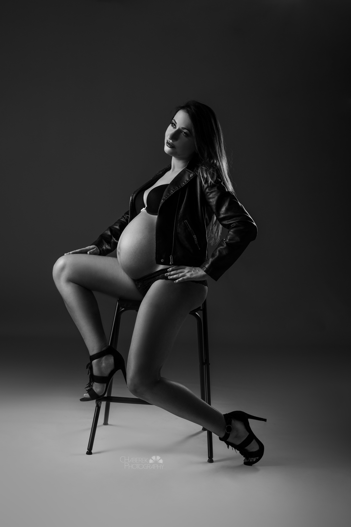 kobieta w ciąży siedząca na wysokim krześle w studiu fotograficznym